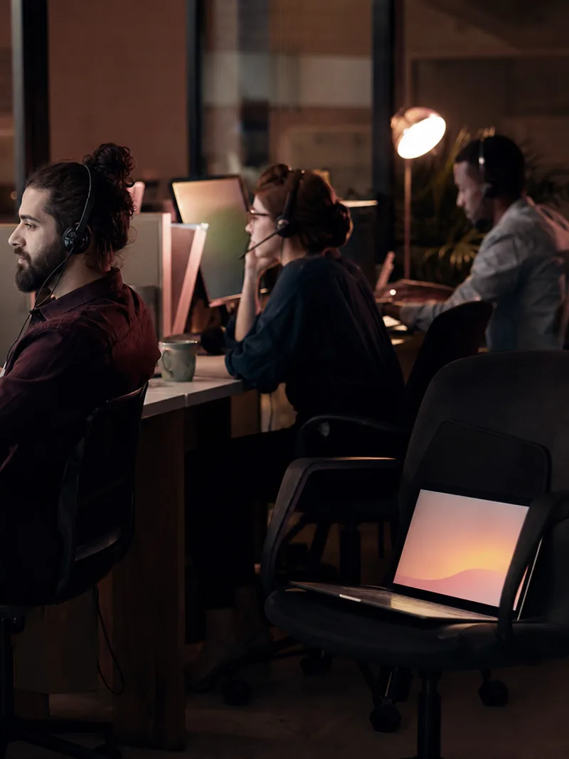 Night shift chat team at desks in an agency office with one empty seat